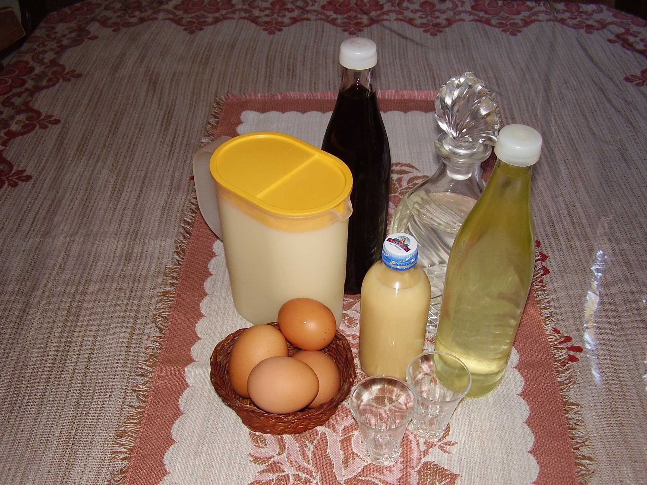 A table with a cloth, a basket of eggs, a jug, a bottle, and a glass.