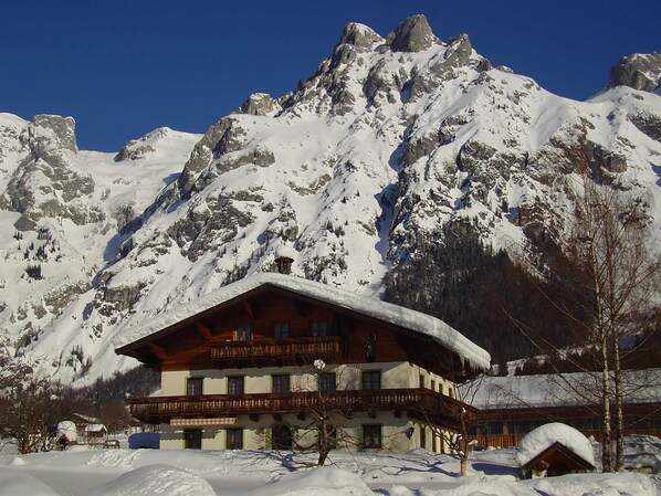 A mountain lodge with a wooden facade, multiple balconies, and a snow-covered roof.