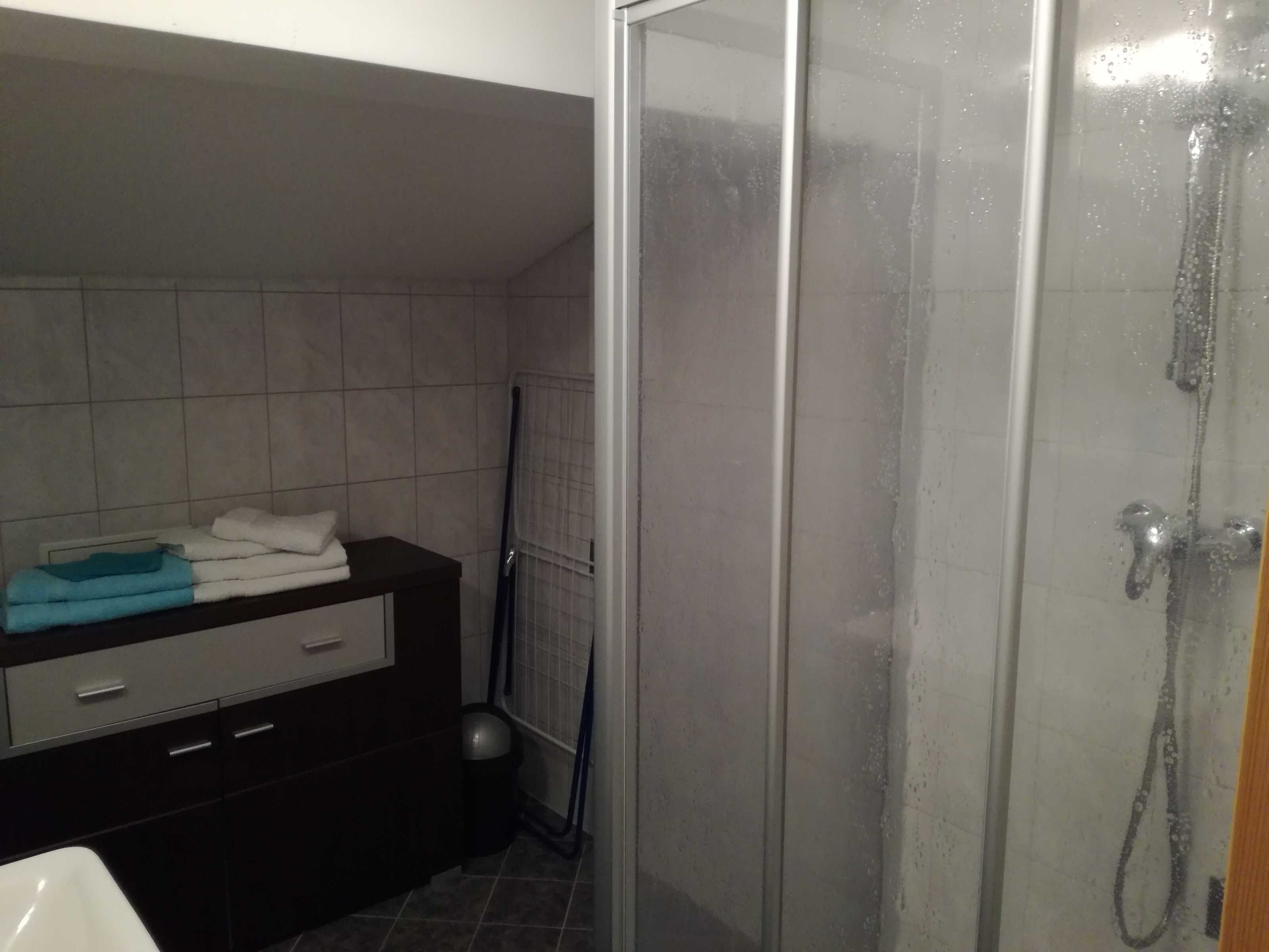 A bathroom with a shower, a sink, and a dark-colored vanity with a towel.