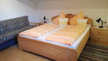 A bedroom with a bed, two bedside tables, a nightstand, a sofa, and a patterned throw.