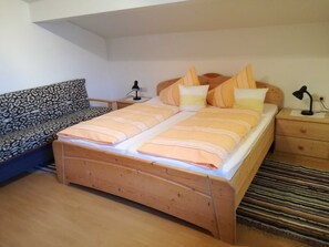 A bedroom with a bed, two bedside tables, a nightstand, a sofa, and a patterned throw. - Apartment Edelweiss-Olgurt (Weng)