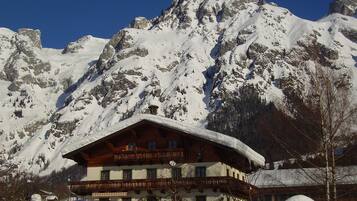 A mountain lodge with a wooden facade, multiple balconies, and a snow-covered roof.