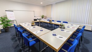A conference room with a whiteboard, a plant, and a table with chairs and a laptop. - Hotel DH VEC (Vechta)