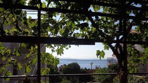 Un balcón con vista al mar, una pérgola y una jardinera de piedra.