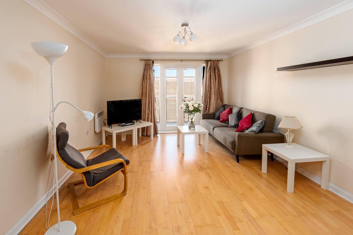 A living room with a sofa, a chair, a coffee table, a TV, and a lamp.