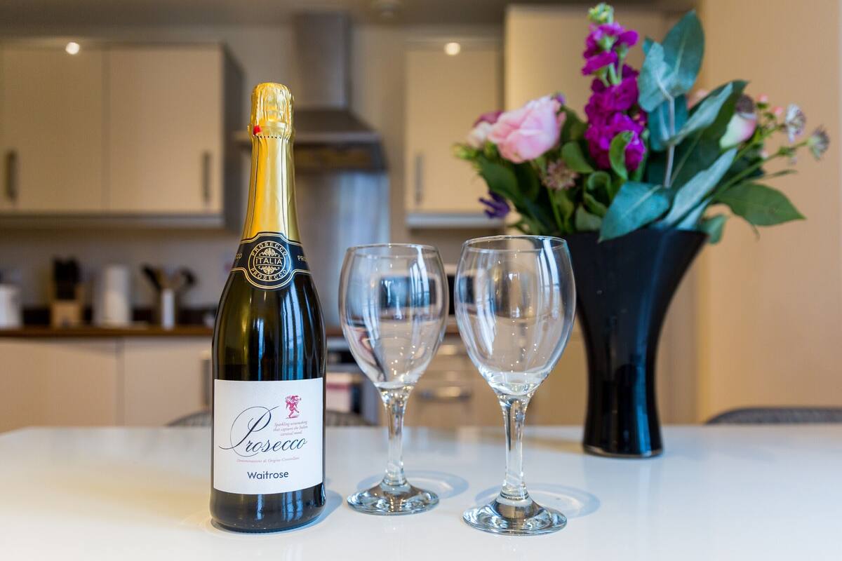 A bottle of Prosecco wine and two empty wine glasses on a table.