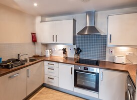 Una cocina moderna con armarios blancos, una campana de acero inoxidable, horno empotrado y salpicadero de azulejos.