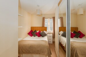 Habitación de hotel con dos camas, un espejo, una mesita de noche y una ventana con cortinas.