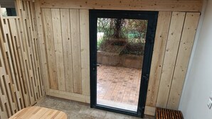 A wooden interior with a sliding door leading to an outdoor area.