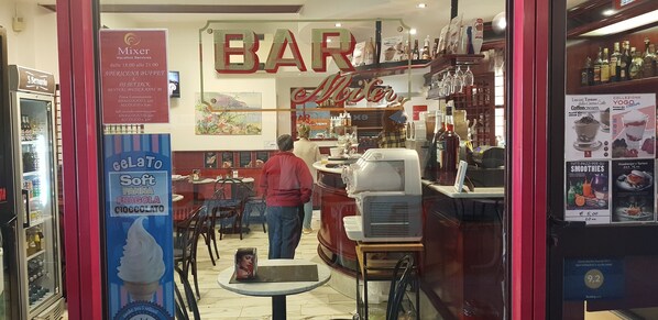 Una zona de bar con mostrador, nevera y cartel de menú.