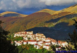 Un pueblo en una ladera con edificios tradicionales, una iglesia destacada y montañas al fondo.