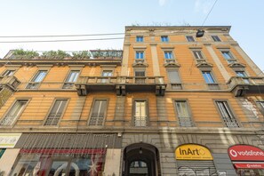 A multi-story building with a yellow facade, a shop on the ground floor, and a Vodafone sign. - notaMi - Tailors' Home Sempione (Milan)