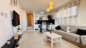 Een moderne woonkamer met een bank, salontafel en een aan de muur bevestigde televisie.