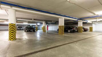 Eine mehrgeschossige Parkgarage mit Betonböden und Säulen, die mit gelb-schwarzen Pfeilen gekennzeichnet sind.