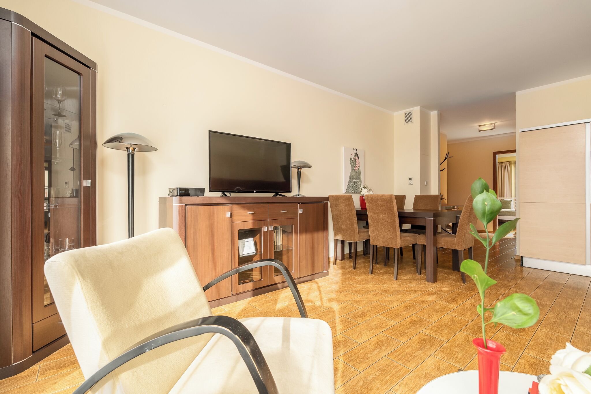 Ein modernes Wohnzimmer mit Flachbildfernseher, Holzmöbeln und einem Essbereich.
