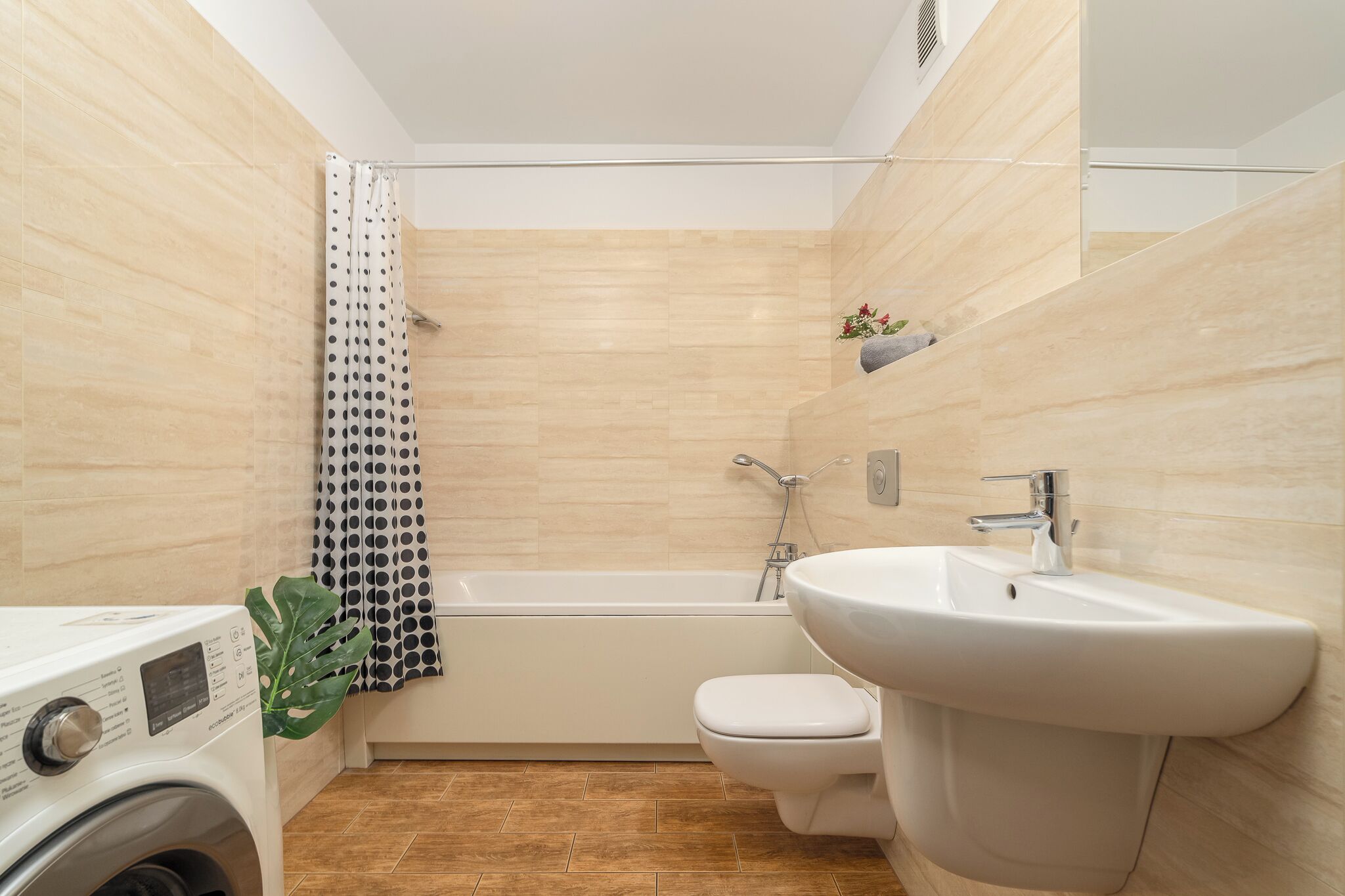 Une salle de bain moderne équipée d’une baignoire, de toilettes et d’un lave-linge.
