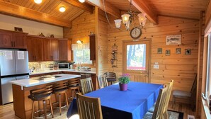 A cabin interior with a kitchen, dining area, and a clock on the wall.