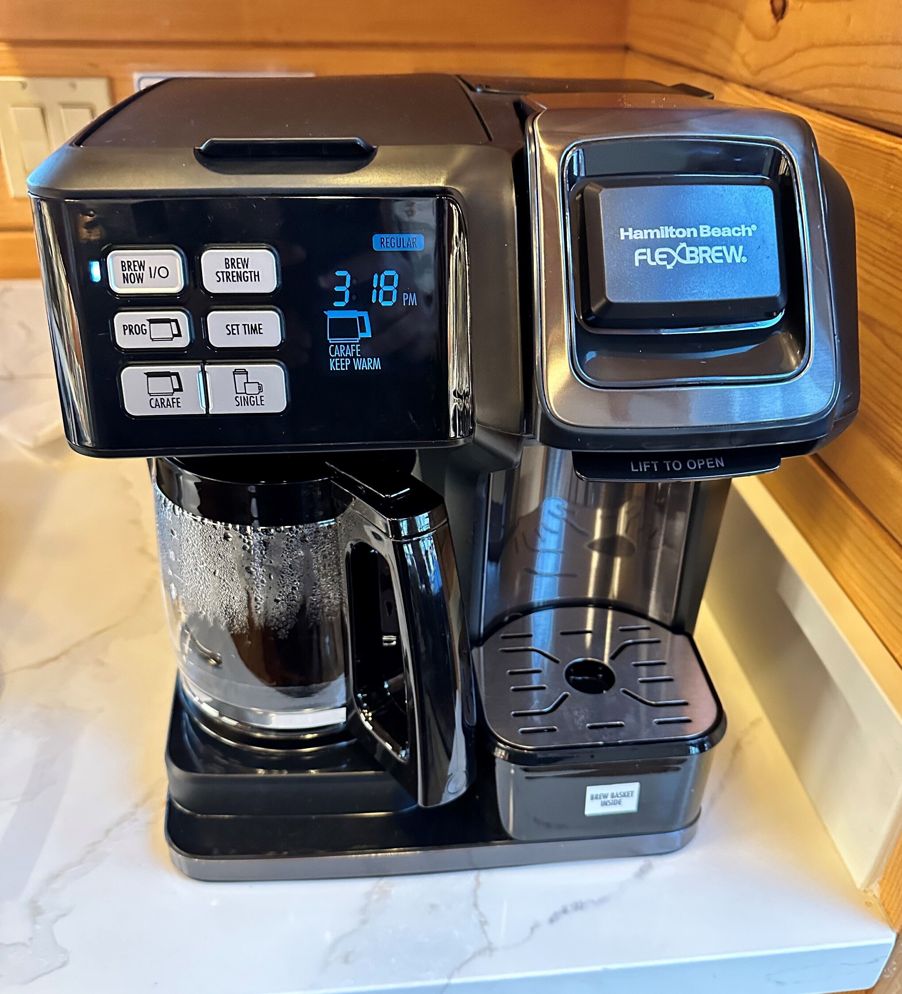 A coffee maker with a digital display, a carafe, and a coffee pot.