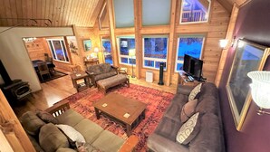 A cozy log cabin interior with a living room, dining area, and large windows.