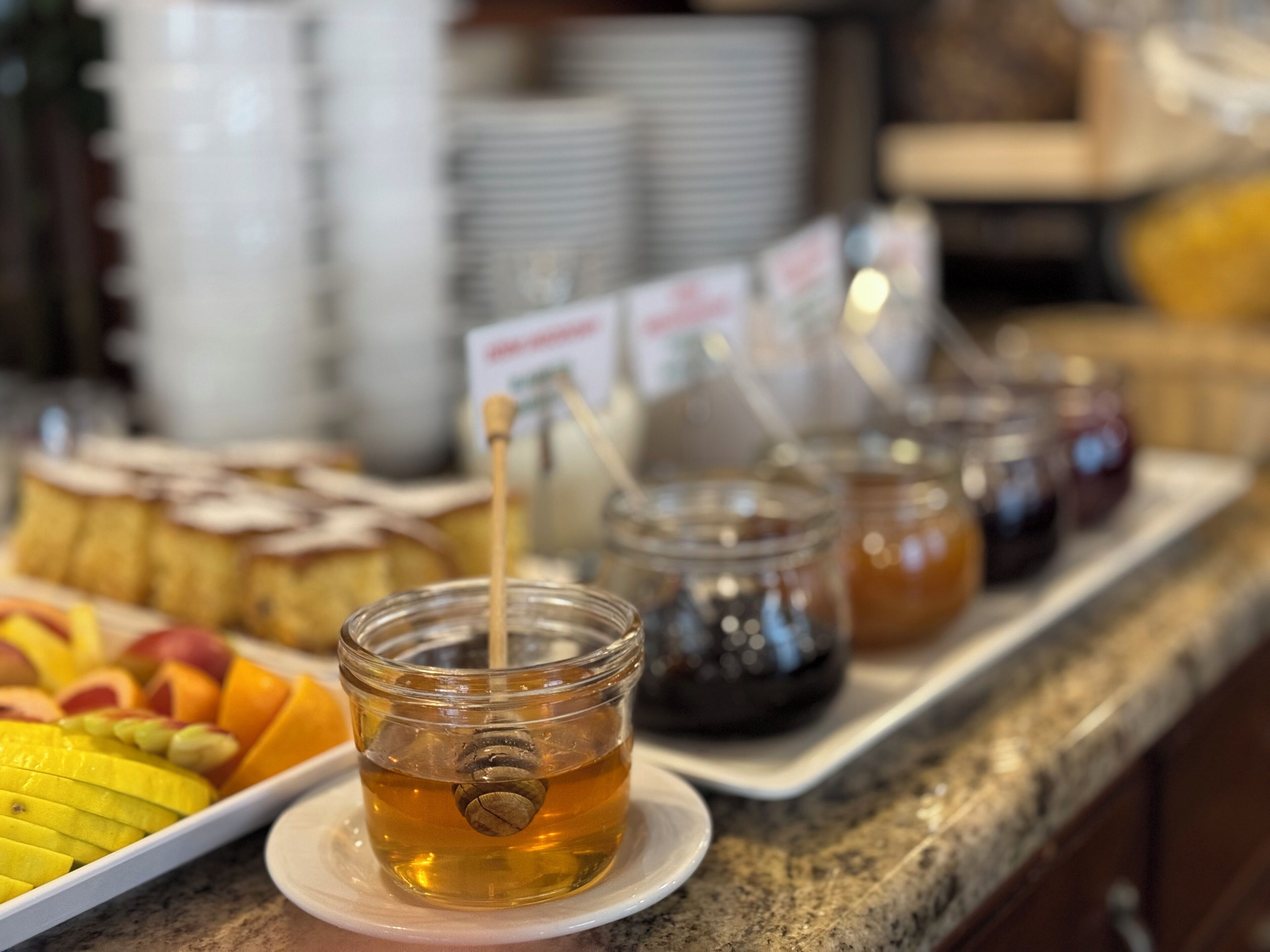 A buffet table with various food items and honey jars.
