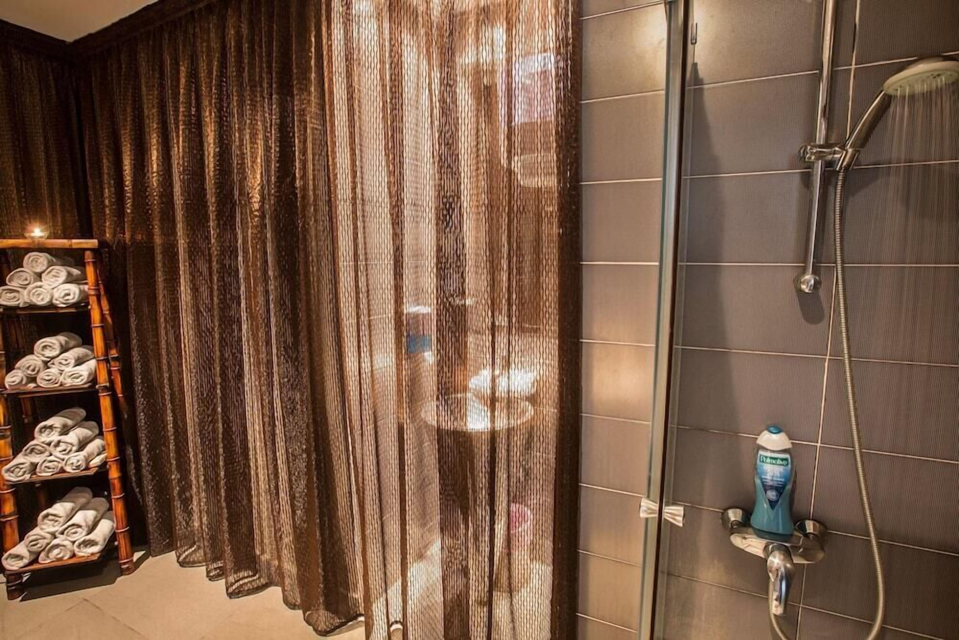 A bathroom with a shower, a towel rack with towels, and a curtain.