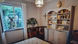 A room with a bed, a bookshelf, a cabinet, and a window with a view of trees. - WHITE & BLUE HOUSE (Chiavari)