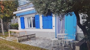 A building with blue shutters, outdoor seating, and a stone-paved patio. - WHITE & BLUE HOUSE (Chiavari)