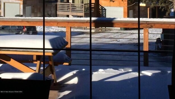 Un bâtiment moderne doté d’une terrasse en bois et offrant une vue sur des montagnes enneigées.