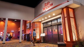 Het uiterlijk van restaurant Red Willow, met een bord, een getextureerd tapijt en een persoon die loopt.