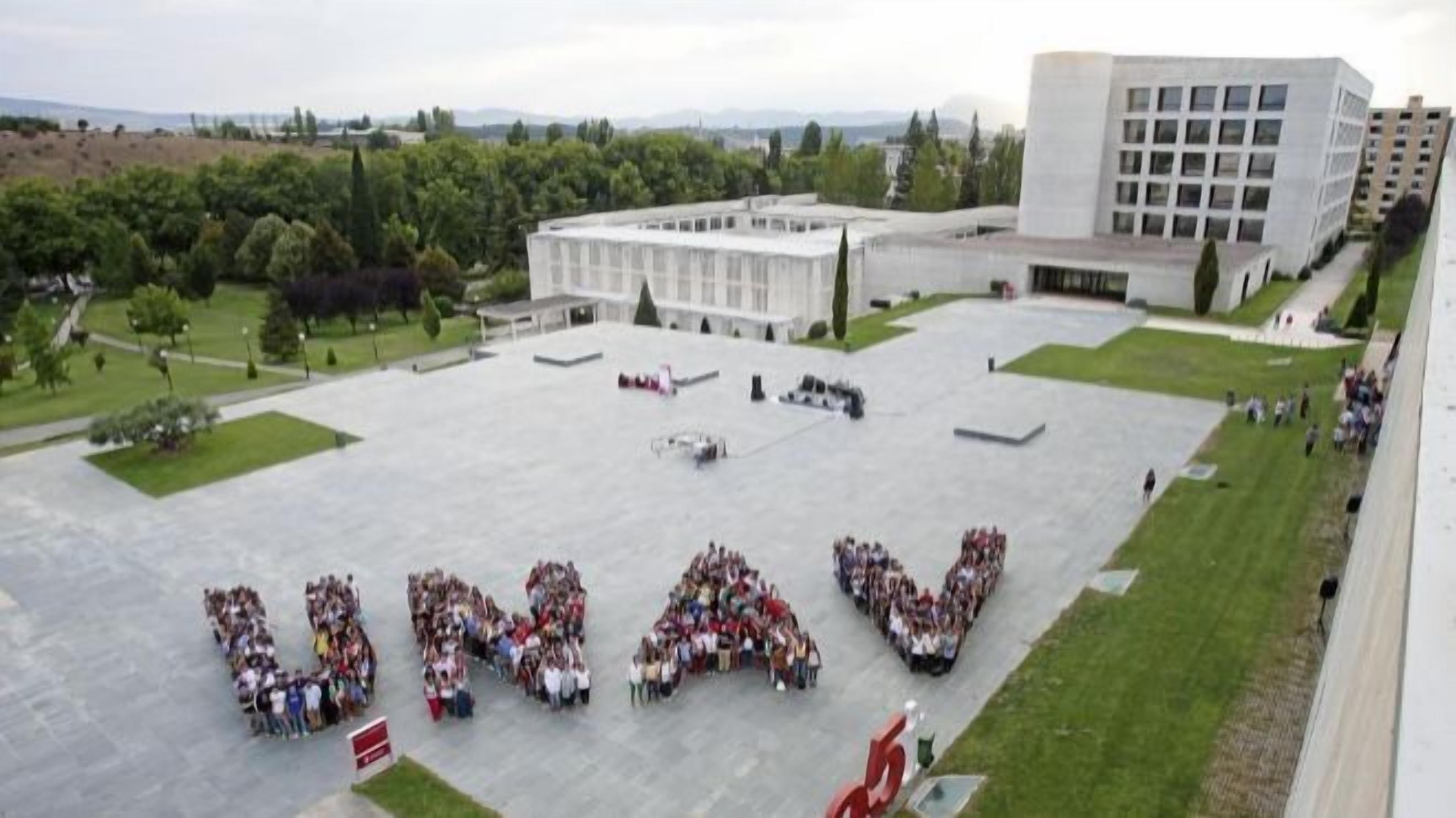 Een groot, open plein waar een menigte de letters “UNAV” vormt.