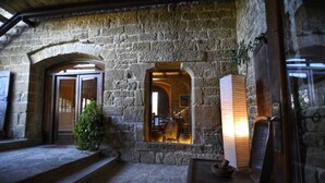 A stone building with arched doorways, a small staircase, and a wooden table with a lamp. - Palacio de Orisoain (Orísoain)