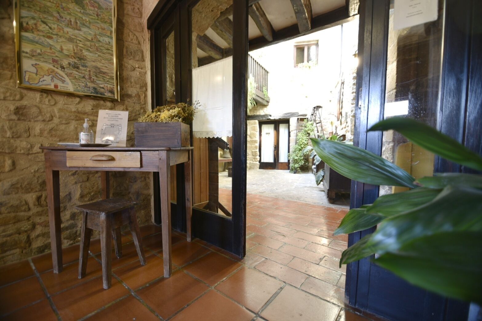 A rustic room with a wooden desk, a chair, and a large potted plant.