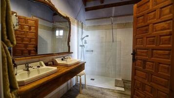 A bathroom with two sinks, a shower, and a wooden door.