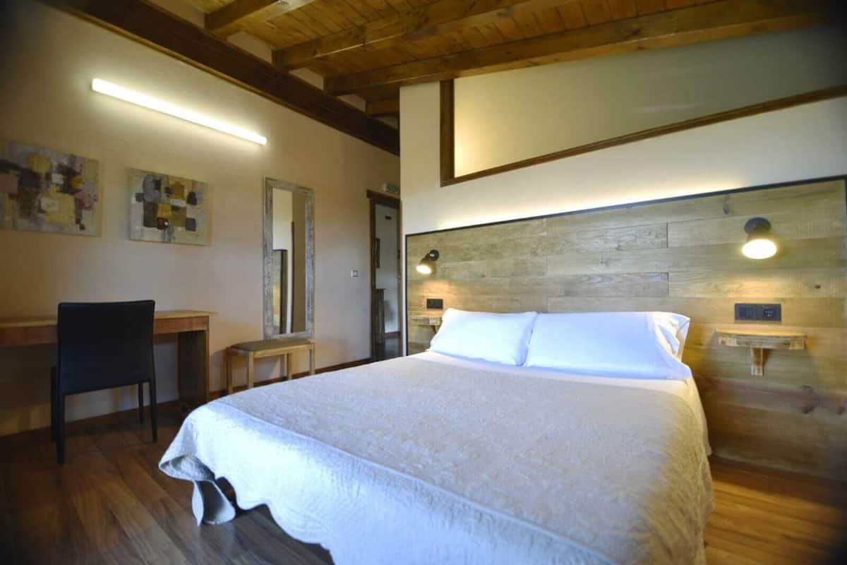 A bedroom with a large bed, a desk, and a chair.