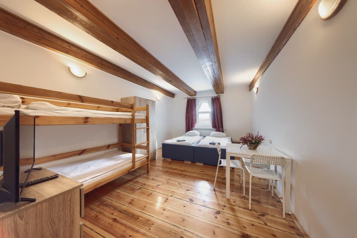A room with a bunk bed, a desk with a chair, and a bed with a window.