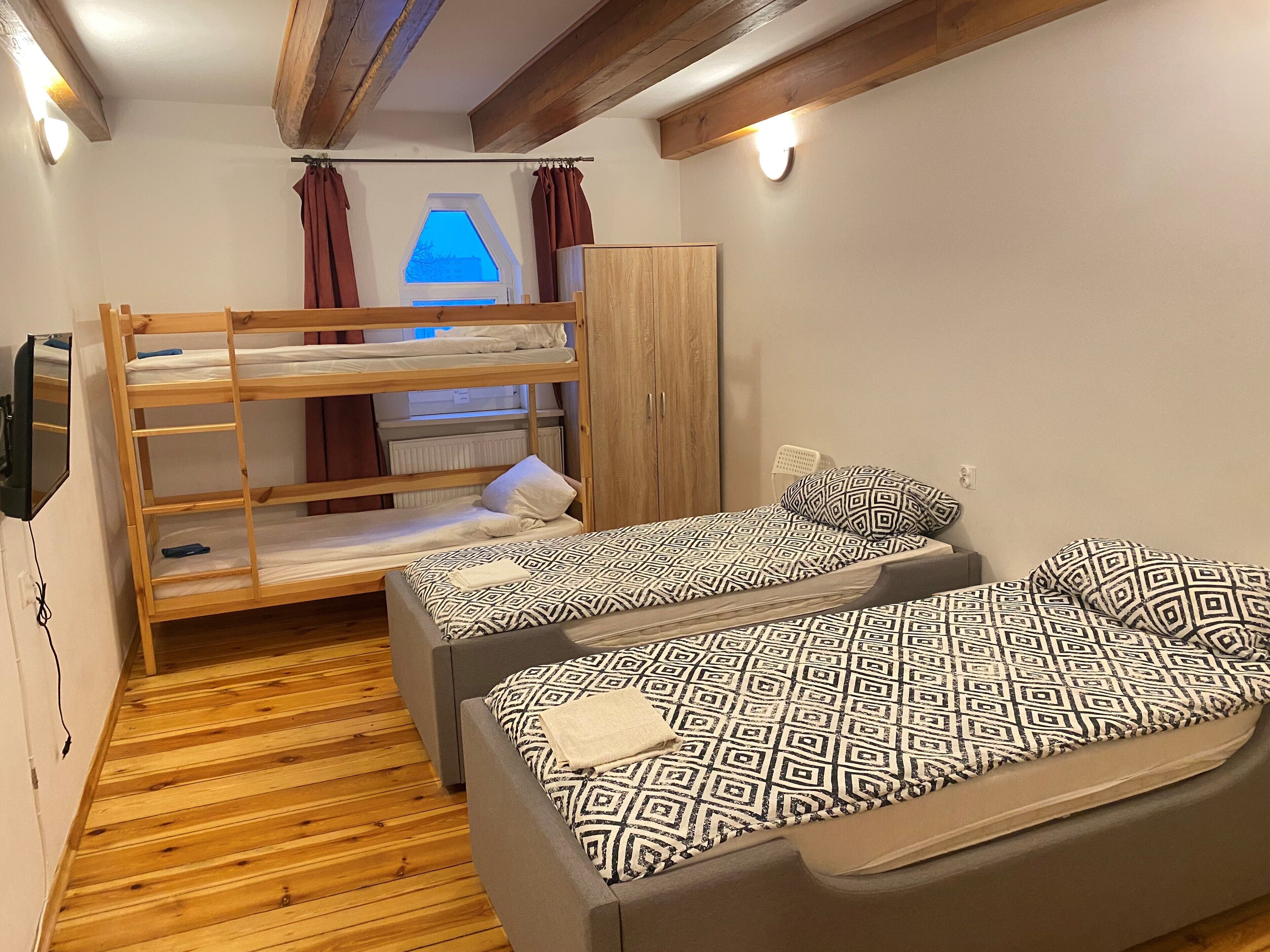 Une chambre avec des lits superposés, une armoire et une fenêtre avec des rideaux.