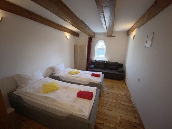 Una habitación pequeña y acogedora con dos camas individuales, un sofá y una ventana con vistas.