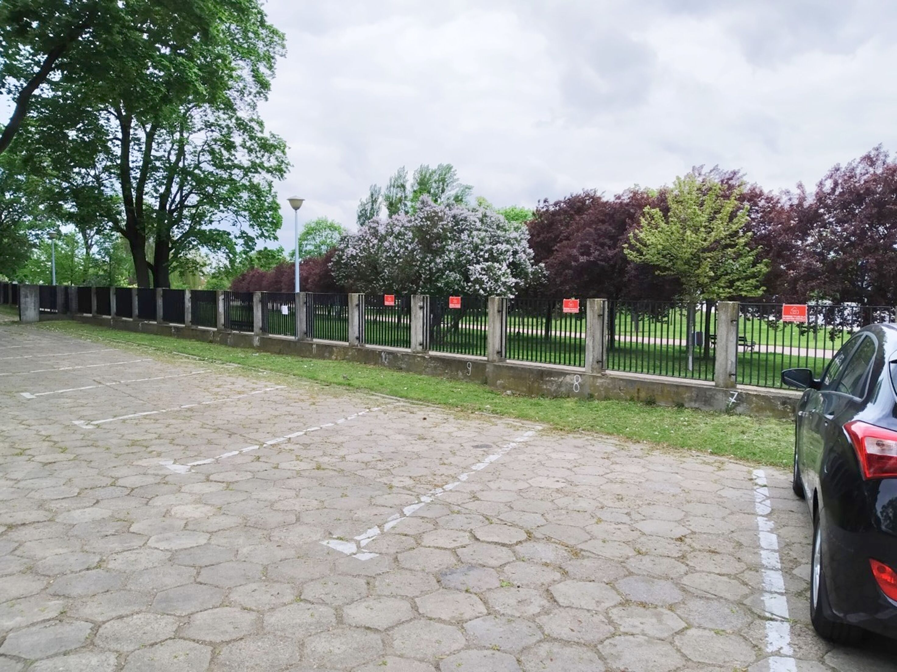 A paved parking area with a black car parked on the right.