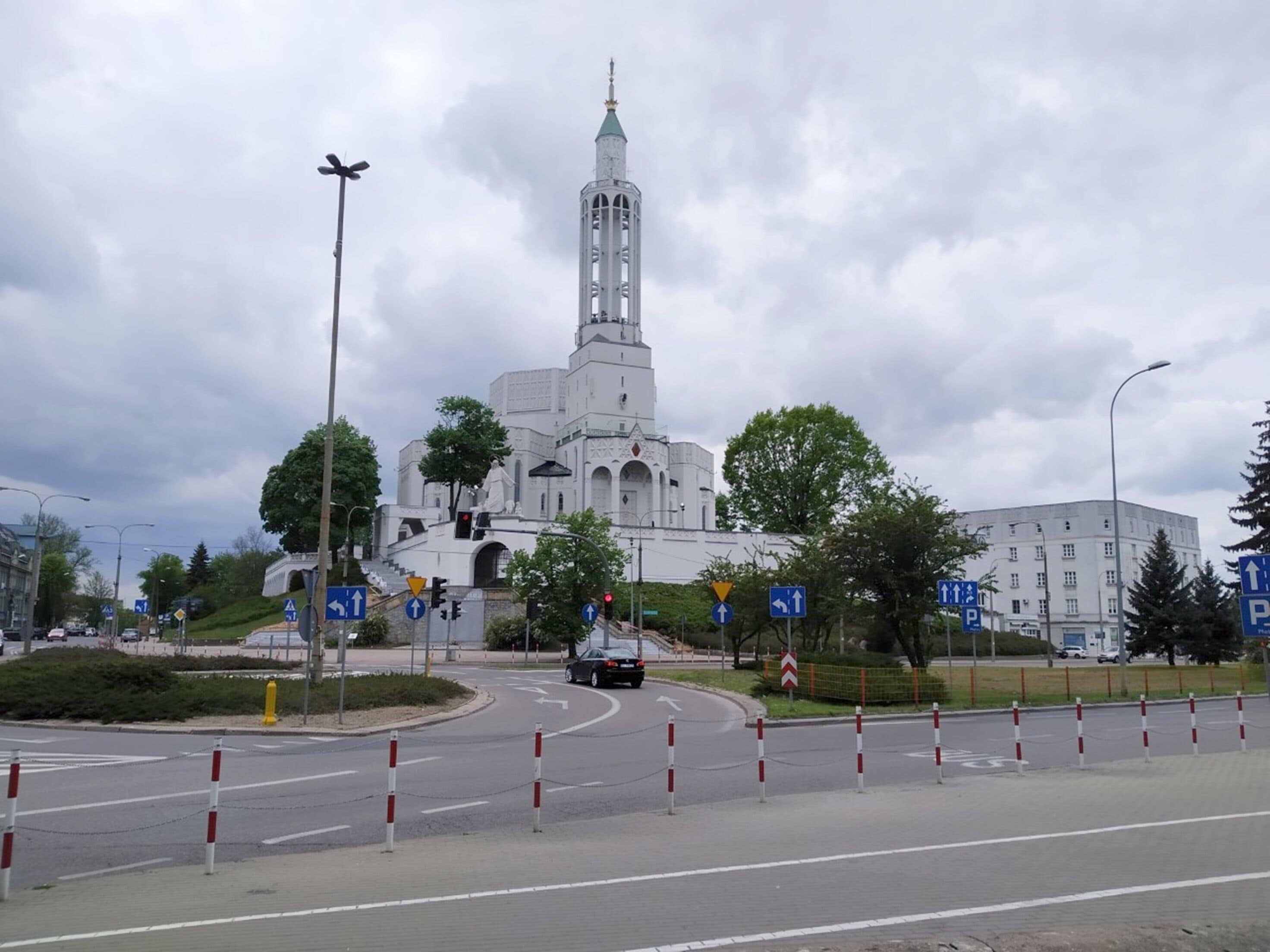 A roundabout with a white building featuring a tower and statue in the center.