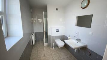 A modern bathroom with a shower, toilet, and sink.