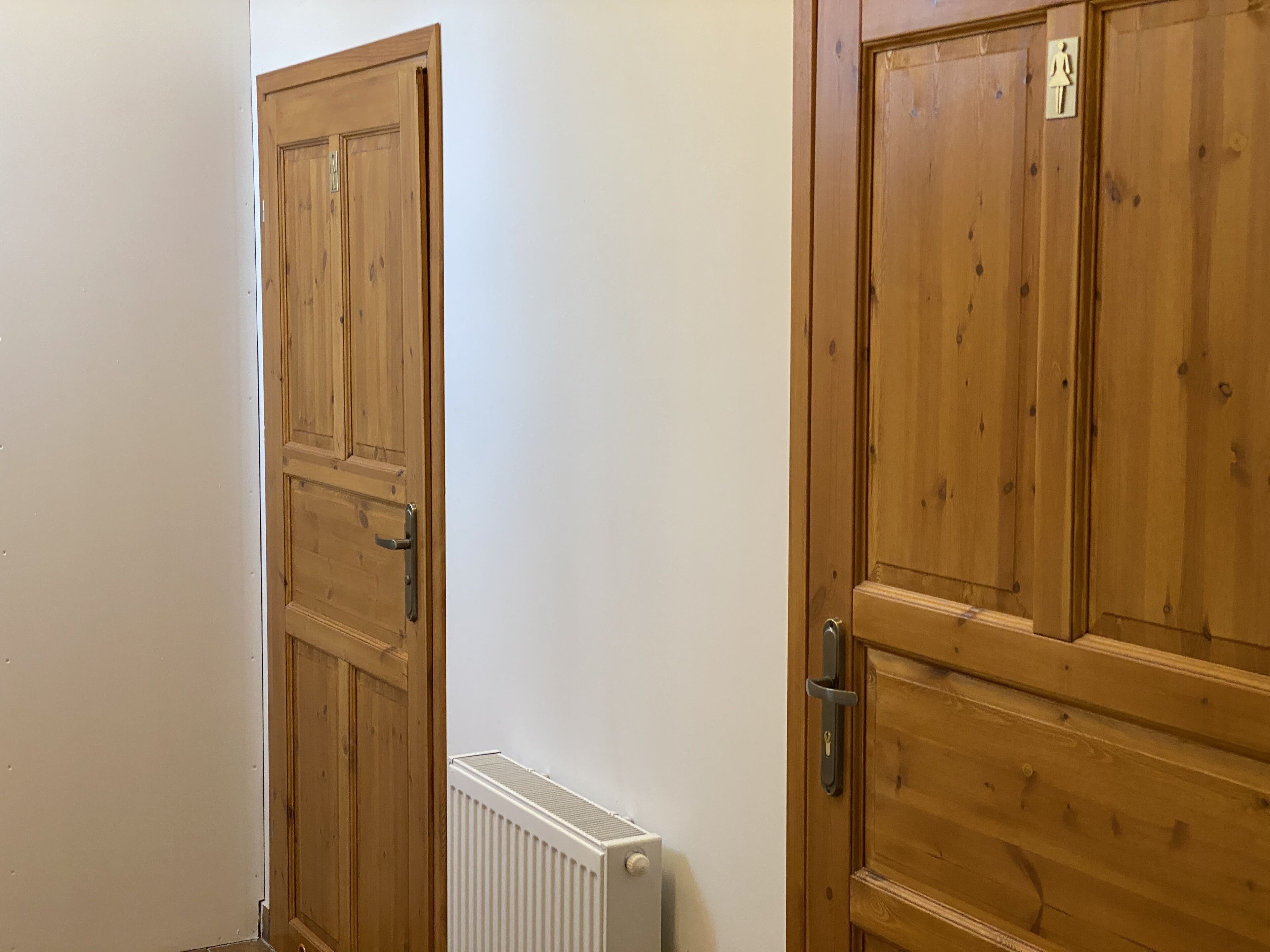 Un pasillo con puertas de madera y un radiador blanco.