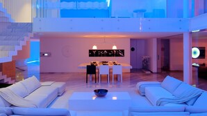 Un interior espacioso y moderno con techo alto, zona de comedor y sala de estar con sofás y una mesa de centro.