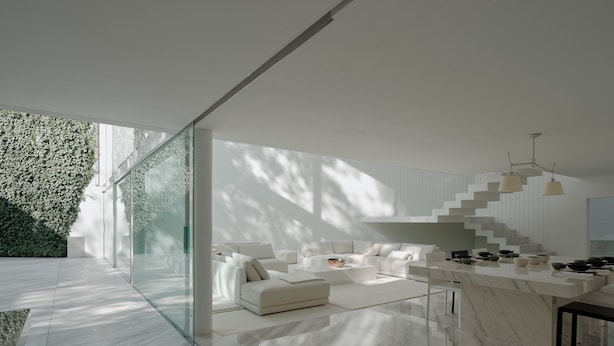 Un interior moderno con un sofá blanco, suelo de baldosas de mármol y una escalera de diseño único.