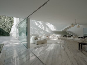 Ein modernes Interieur mit einer weißen Sofagarnitur, einem Marmorboden und einer Treppe mit einem einzigartigen Design.