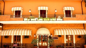 A hotel with a warm orange facade, a central entrance with a sign reading "HOTEL CERCONE," and outdoor seating with potted plants. - Hotel Cercone (Caramanico Terme)