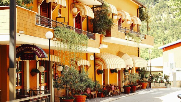 A hotel with a balcony, outdoor seating, and potted plants. - Hotel Cercone (Caramanico Terme)