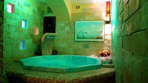 A bathroom with a large bathtub, tiled walls, and a picture on the wall. - Hotel Cercone (Caramanico Terme)