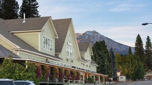A hotel with a mountain backdrop, featuring a prominent entrance with outdoor seating and string lights.