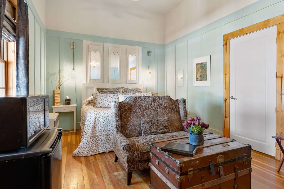 Un dormitorio acogedor con cama, sofá, cómoda, maleta y televisor.