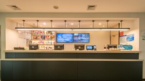 A reception desk with multiple monitors, a digital display, and a counter with various items.